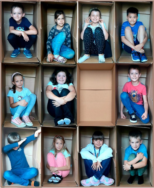 dzieci pozują do zdjęcia, siedząc kartonowych pudełkach, które są ramką.