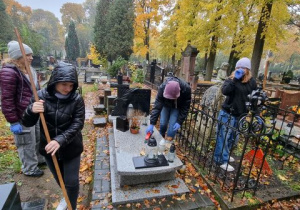 uczniowie sprzątają liście wokół starych grobów na Starym Cmentarzu.