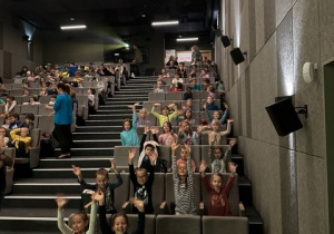 uczniowie siedzący w sali kinowej.
