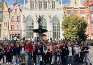 Dzieci stoją przed pomnikiem Neptuna w Gdańsku