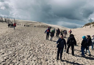 Grupa dzieci idzie po piasku na ruchome wydmy