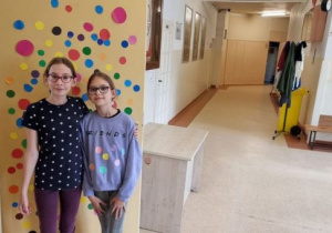 dwie dziewczynki w bluzkach w kropki na tle kolorowych kropek