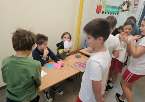Uczniowie na korytarzu szkolnym, biorą udział w zabawach andrzejkowych.