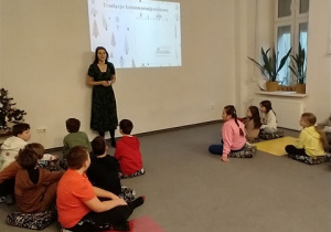 Dzieci z klasy 3b siedzą w dużej sali przed ekranem.