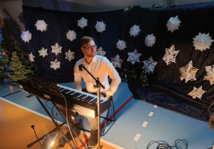 Nauczyciel muzyki przy instrumencie klawiszowym na tle dekoracji świątecznej