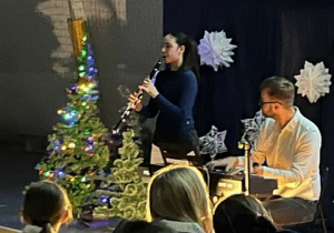 Maja z 6a gra kolędę na klarnecie przy akompaniamencie nauczyciela muzyki.