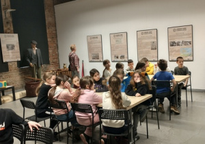 Uczniowie siedzą przy stolikach podczas warsztatów w Muzeum.