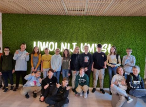 Duża grupa dzieci stoi na tle zielonej ściany z napisem: Uwolnij umysł