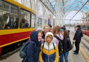 chłopcy stoją na tle czerwono żółtych tramwajów