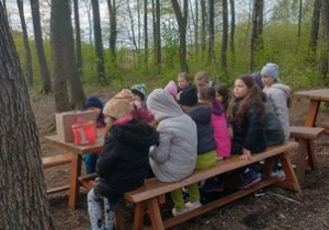 Grupa uczniów podczas zajęć przetrwania w lesie.