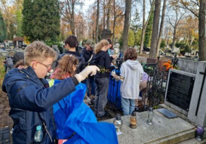 dzieci sprzątające groby na cmentarzu
