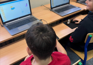 Uczniowie przed ekranami laptopów - programują w Scratch.