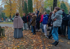 Młodzież w jesiennej scenerii na Cmentarzu przy jednym z pomników.