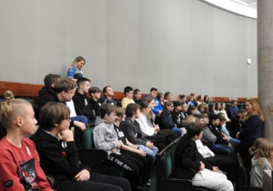 Uczniowie klas 8 siedzący na galerii w sali posiedzeń Sejmu RP