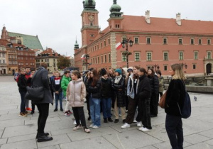 Uczniowie stoją na tle budynku Zamku Królewskiego w Warszawie