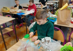 Uczniowie klasy 4 podczas lekcji przyrody przygotowują zdrowe kanapki.