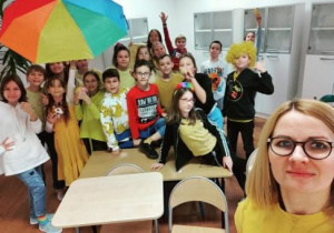 Dzieci ubrane na żółto pod kolorowym parasolem