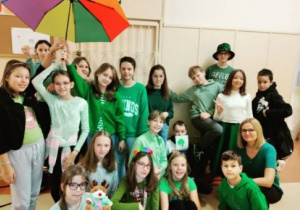 Dzieci ubrane na zielono pod kolorowym parasolem