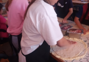 Uczestnicy półkolonii podczas warsztatów pieczenia pizzy.