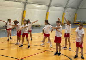 Dzieci ćwiczą w hali sportowej.