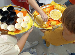 Tace z lemoniadą w kubkach i talerzyki z cytryną.