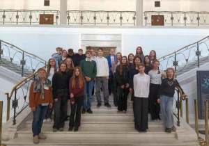 Klasy 8 pozują do zdjęcia na schodach w Sejmie.