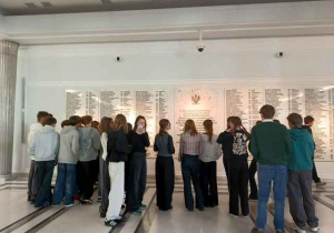 Sejm - uczniowie stoją przed ścianą Pamięci.