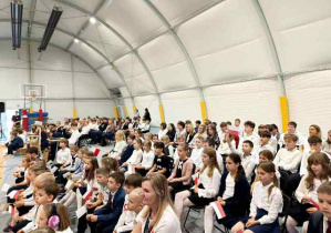 Uczniowie zebrani w hali podczas uroczystości.