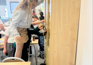 Uczniowie mierzą wysokość szafki.