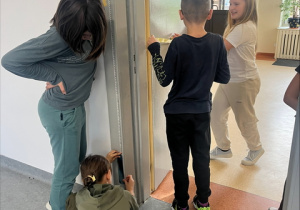 Pomiar wysokości futryny drzwiowej przez grupę uczniów z klasy 4.