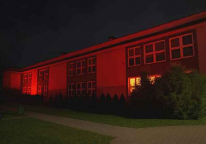 Budynek szkoły oświetlony na czerwono.