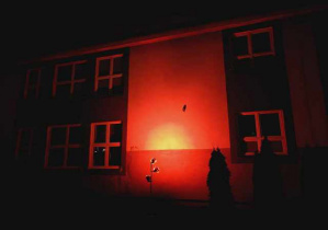 Budynek szkoły wieczorową porą podświetlony na czerwono.