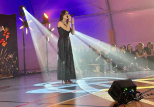 Kobieta śpiewająca na scenie.