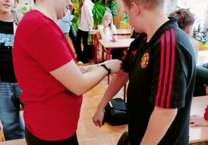 Zakładanie opaski uciskowej podczas ćwiczeń z pierwszej pomocy.