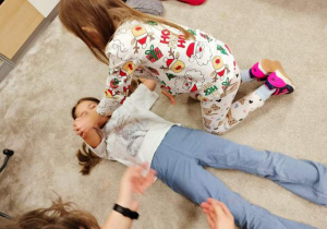 Dziewczynki uczą sie układać w pozycji bezpiecznej podczas warsztatów z udzielania pierwszej pomocy.