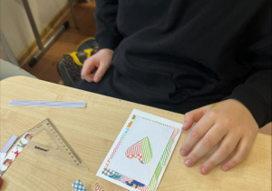 Uczeń pracuje nad wykonaniem walentynkowej karty.