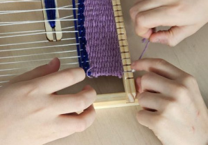 Uczniowie tkają na krośnie.