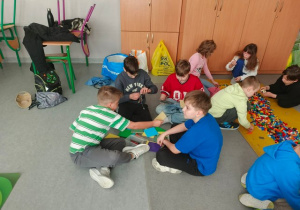 Grupy uczniów układają budowle z klocków Lego.