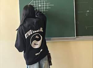 Uczennica na tablicy rozwiązuje zagadnienie matematyczne.