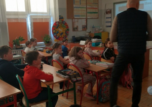 Dzieci siedzą w ławkach w klasie
