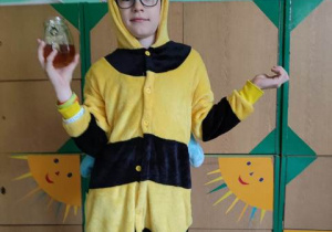 Chłopiec w stroju pszczoły ze słoikiem miodu.