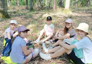 5 dziewczynek siedzi w lesie na ziemi