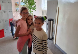 3 dziewczynki z 4a stoją na korytarzu szkolnym.