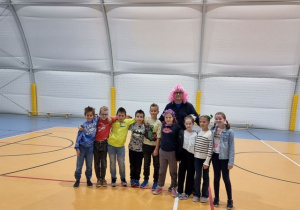 Wychowawca 4a w różowej peruce z uczniami swojej klasy na hali sportowej.